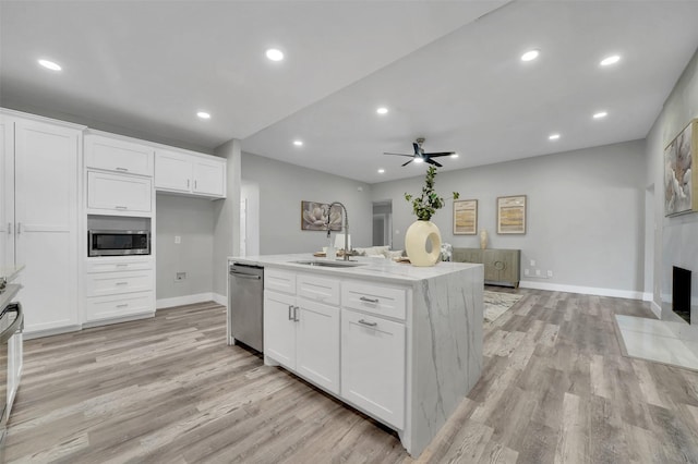 kitchen featuring white cabinets, stainless steel appliances, light wood-style flooring, a sink, and ceiling fan