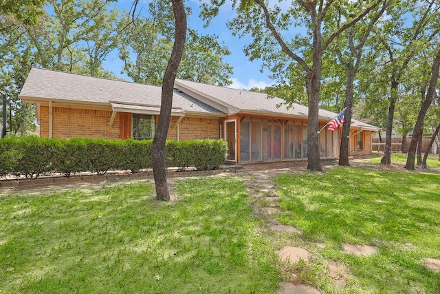 view of front of property with brick siding, a front lawn, and a sunroom