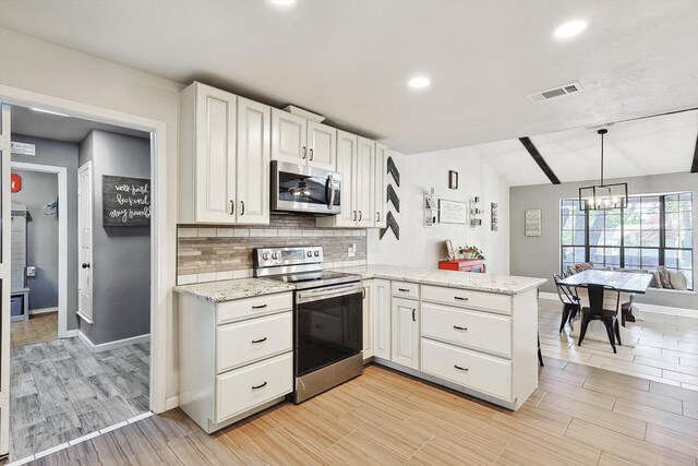 kitchen with visible vents, a peninsula, stainless steel appliances, decorative backsplash, and white cabinetry