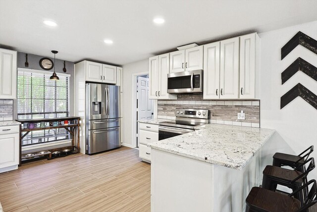 kitchen with white cabinetry, a peninsula, backsplash, and stainless steel appliances