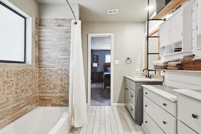 ensuite bathroom featuring visible vents, ensuite bathroom, wood finished floors, shower / bath combination with curtain, and vanity