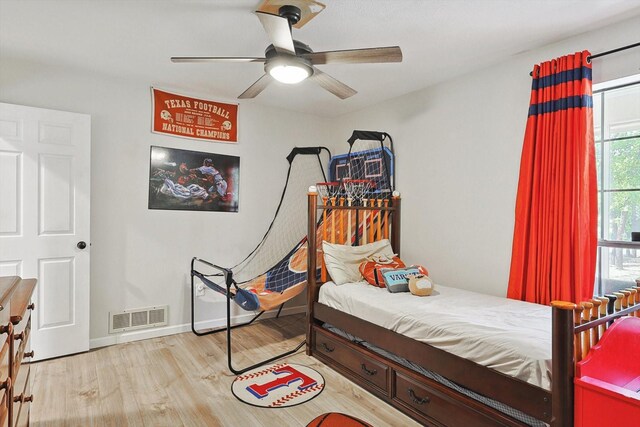 bedroom featuring ceiling fan, visible vents, baseboards, and wood finished floors