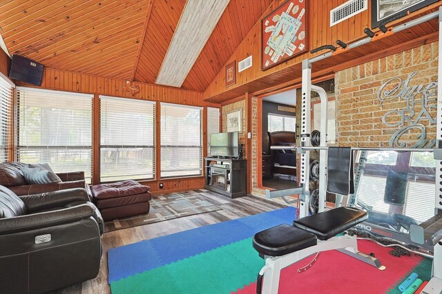 living area with plenty of natural light, wooden walls, lofted ceiling, and wood finished floors