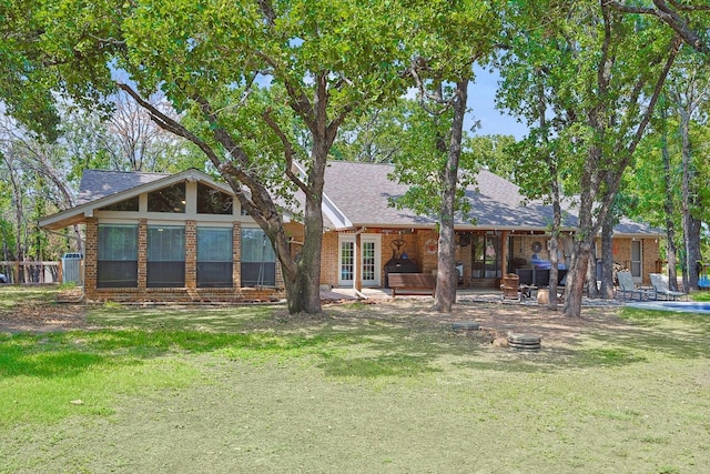 back of property featuring a yard, brick siding, a patio, and a shingled roof