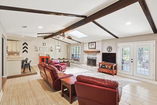 living area with wood finish floors, visible vents, lofted ceiling with skylight, and ceiling fan with notable chandelier