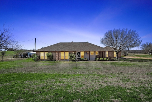 view of front of house featuring brick siding, a front lawn, and fence