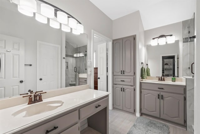 full bathroom featuring a stall shower, two vanities, and a sink