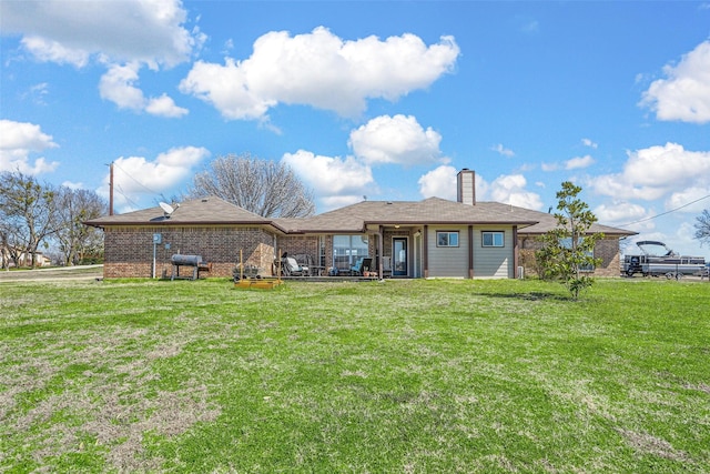 back of property with brick siding, a lawn, and a chimney