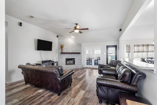 living room with visible vents, wood finished floors, a fireplace, ceiling fan, and vaulted ceiling