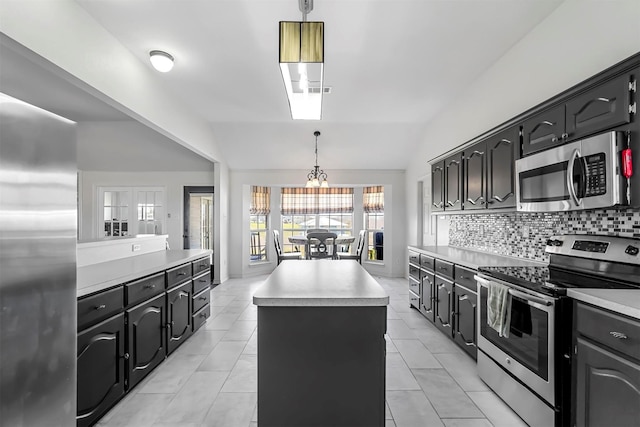 kitchen with tasteful backsplash, a kitchen island, stainless steel appliances, light countertops, and vaulted ceiling