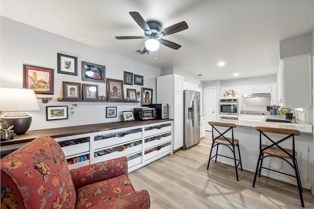 1605 Tampico Dr, Plano, TX 75075 - kitchen with stainless steel appliances, under cabinet range hood, a peninsula, white cabinets, and a kitchen bar