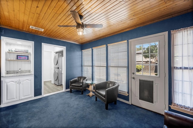 1605 Tampico Dr, Plano, TX 75075 - living area featuring stacked washing machine and dryer, wood ceiling, a ceiling fan, carpet flooring, and crown molding