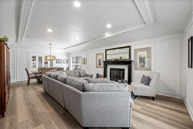 1605 Tampico Dr, Plano, TX 75075 - living room with a decorative wall, a glass covered fireplace, light wood finished floors, a chandelier, and recessed lighting