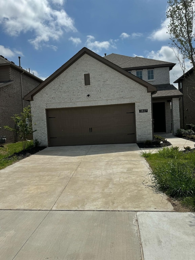 view of front of property with an attached garage, brick siding, and driveway