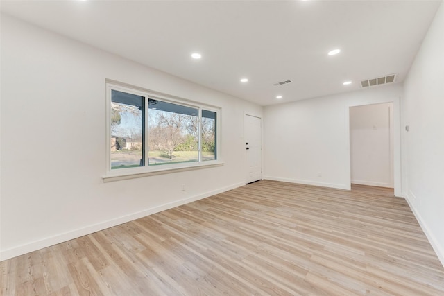 spare room featuring baseboards, visible vents, and light wood-type flooring