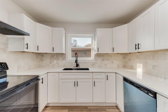 kitchen featuring dishwashing machine, black electric range oven, white cabinetry, wall chimney exhaust hood, and a sink