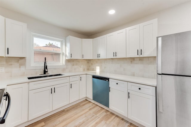 kitchen with light wood-style flooring, a sink, freestanding refrigerator, white cabinets, and dishwashing machine