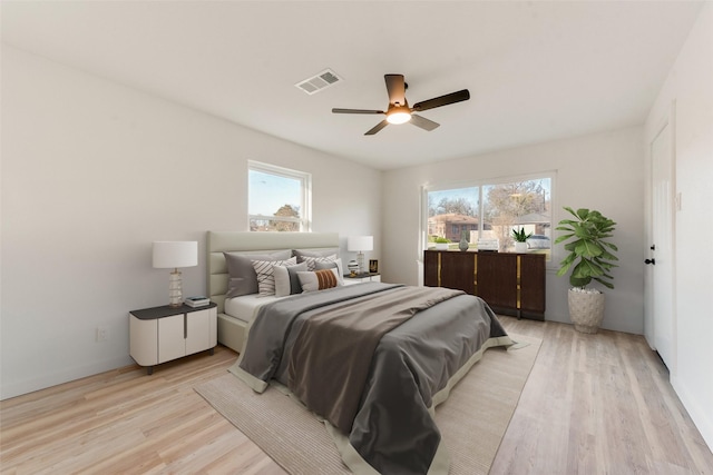 bedroom with light wood-style flooring, a ceiling fan, and visible vents