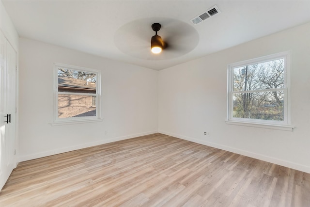 unfurnished room with visible vents, a healthy amount of sunlight, light wood-type flooring, and baseboards