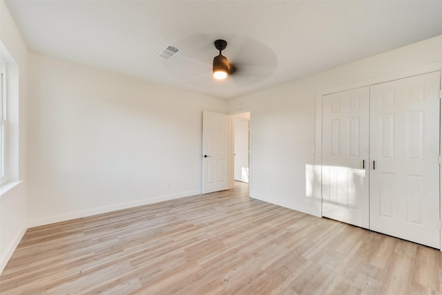 unfurnished bedroom featuring light wood-type flooring, visible vents, baseboards, and a closet