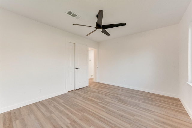 spare room with a ceiling fan, light wood-style floors, visible vents, and baseboards