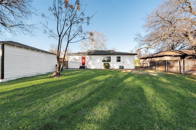 back of house with an outbuilding, a yard, fence, and central AC