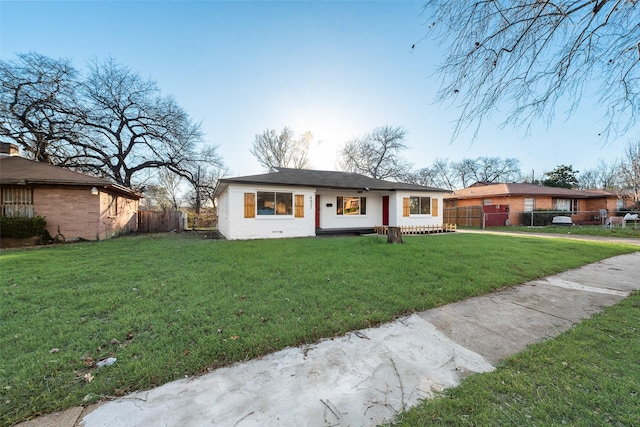 view of front of home with a front lawn, fence, and brick siding