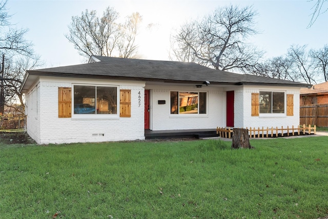 view of front of home featuring brick siding, a shingled roof, fence, a front yard, and crawl space