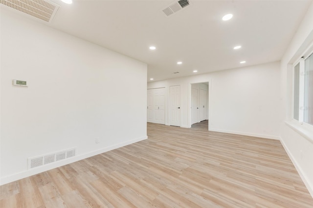 empty room with baseboards, visible vents, and light wood finished floors