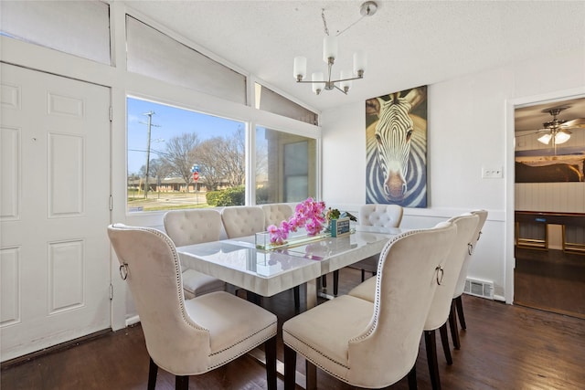 dining area featuring a chandelier, vaulted ceiling, visible vents, and wood finished floors