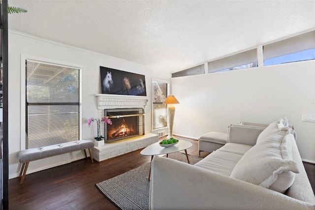 living area with lofted ceiling, a textured ceiling, a brick fireplace, and wood finished floors