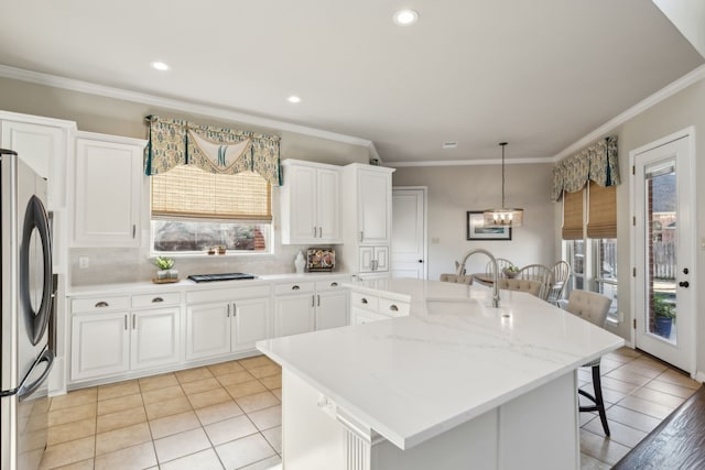 kitchen featuring tasteful backsplash, a kitchen breakfast bar, freestanding refrigerator, white cabinetry, and a sink