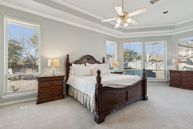 bedroom featuring a tray ceiling, multiple windows, light colored carpet, and ornamental molding