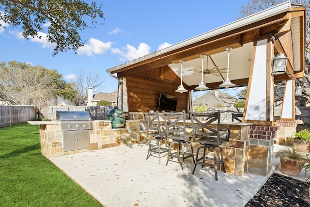 view of patio / terrace with outdoor wet bar, grilling area, a fenced backyard, and an outdoor kitchen