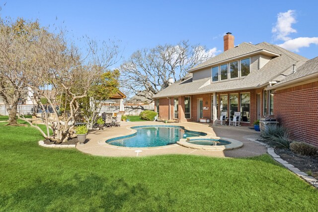 view of pool with fence, a lawn, a pool with connected hot tub, and a patio area