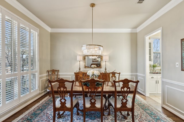 dining space featuring crown molding, wood finished floors, and a chandelier