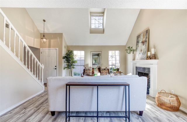 living room with a wealth of natural light, light wood-type flooring, and lofted ceiling