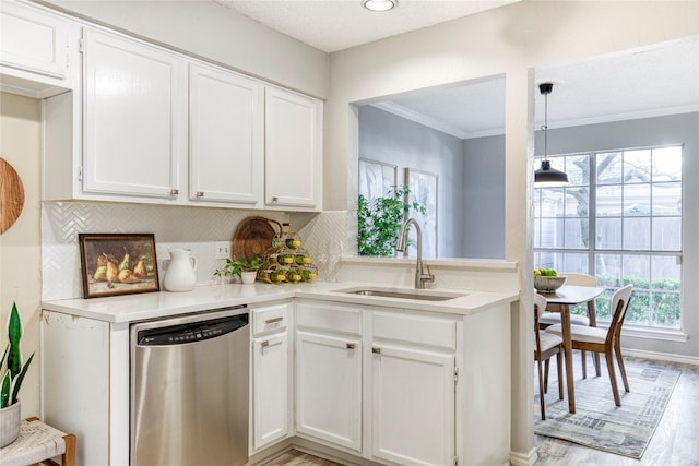 kitchen featuring a sink, light countertops, white cabinets, stainless steel dishwasher, and tasteful backsplash