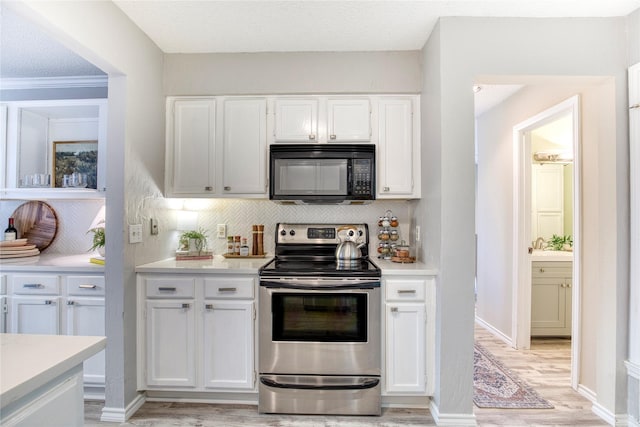 kitchen featuring tasteful backsplash, black microwave, light countertops, stainless steel range with electric stovetop, and white cabinetry