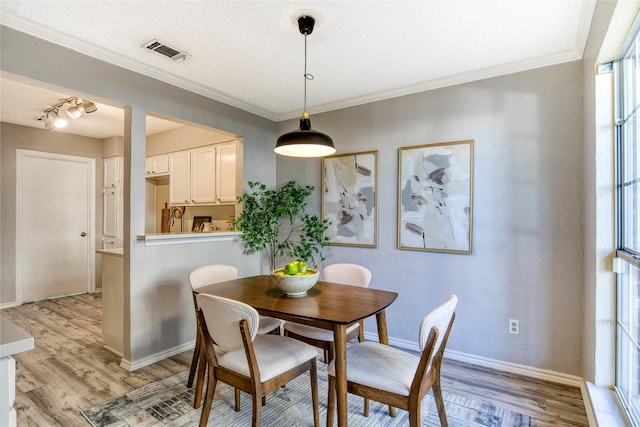 dining area with baseboards, visible vents, a textured ceiling, and light wood-style floors