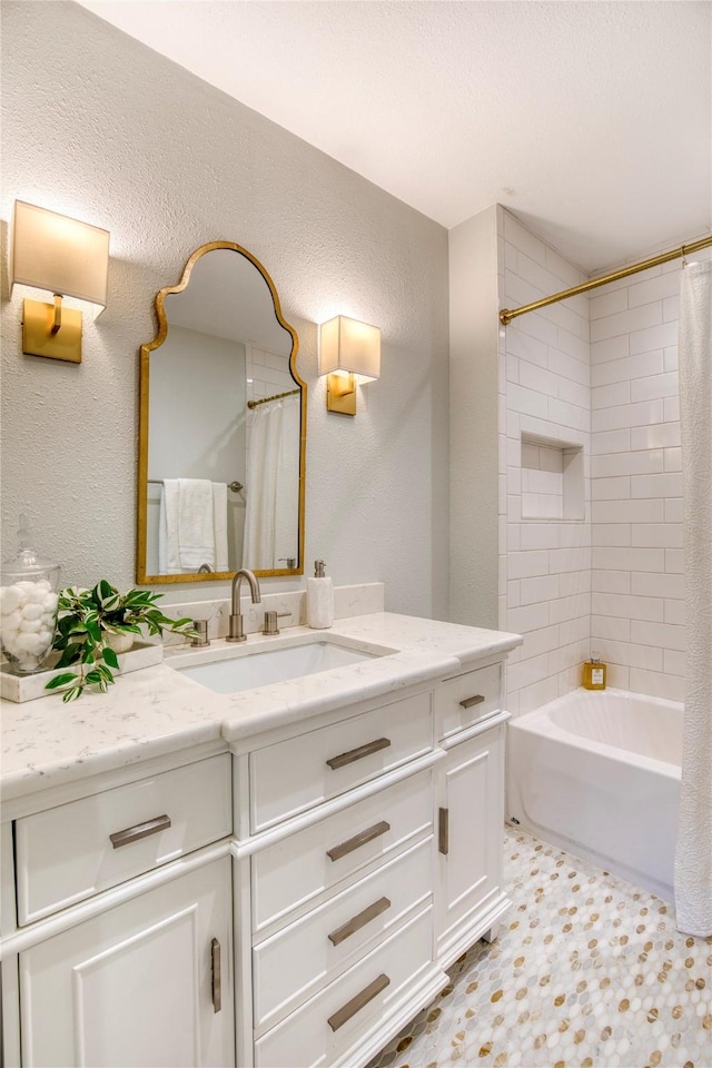 full bath featuring shower / bath combo, vanity, and a textured wall