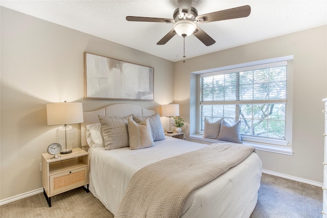 bedroom with light colored carpet, a textured ceiling, baseboards, and a ceiling fan