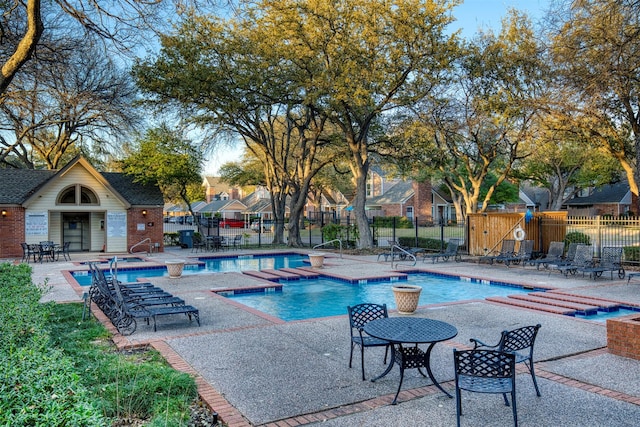 community pool with a patio area, an outbuilding, and fence