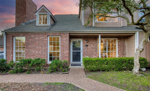 view of front of house with brick siding and roof with shingles