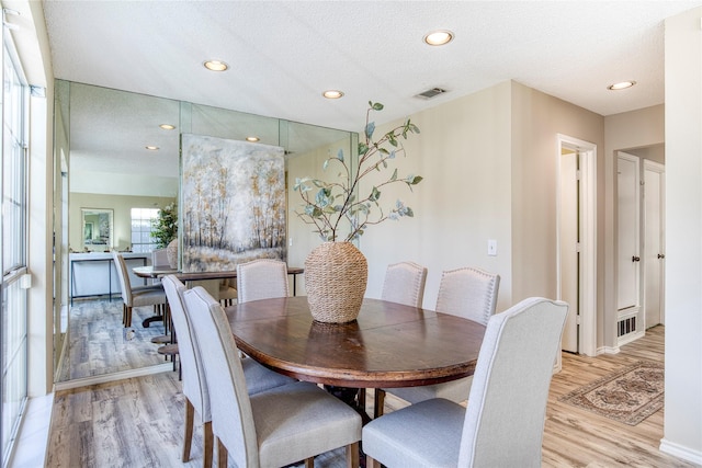 dining room featuring light wood-style floors, visible vents, and a textured ceiling