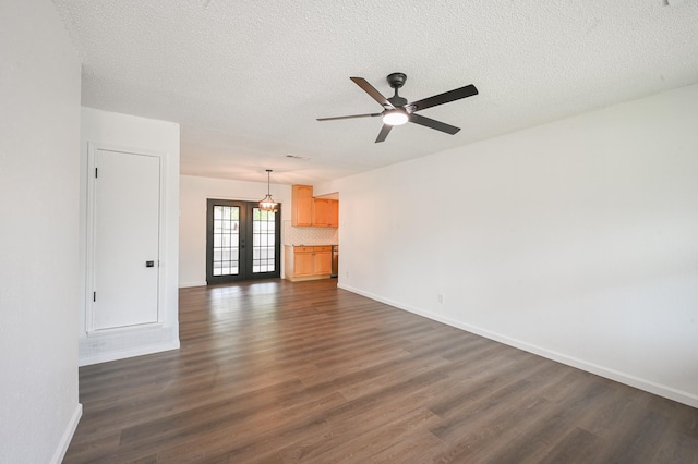 unfurnished living room featuring dark wood-style floors, baseboards, french doors, and a textured ceiling