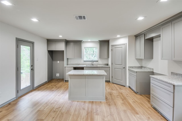 kitchen with a sink, visible vents, gray cabinetry, and a center island