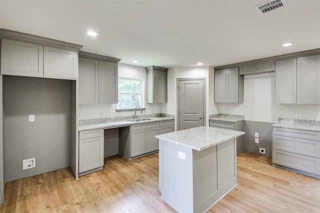 kitchen featuring a sink, visible vents, light wood-style flooring, and gray cabinets