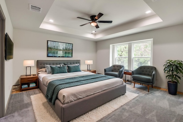 bedroom with baseboards, visible vents, a ceiling fan, and a tray ceiling