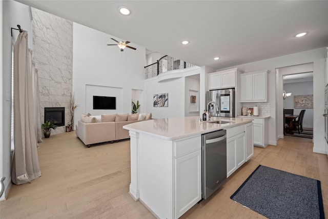 kitchen featuring a premium fireplace, light wood-style floors, appliances with stainless steel finishes, and a sink